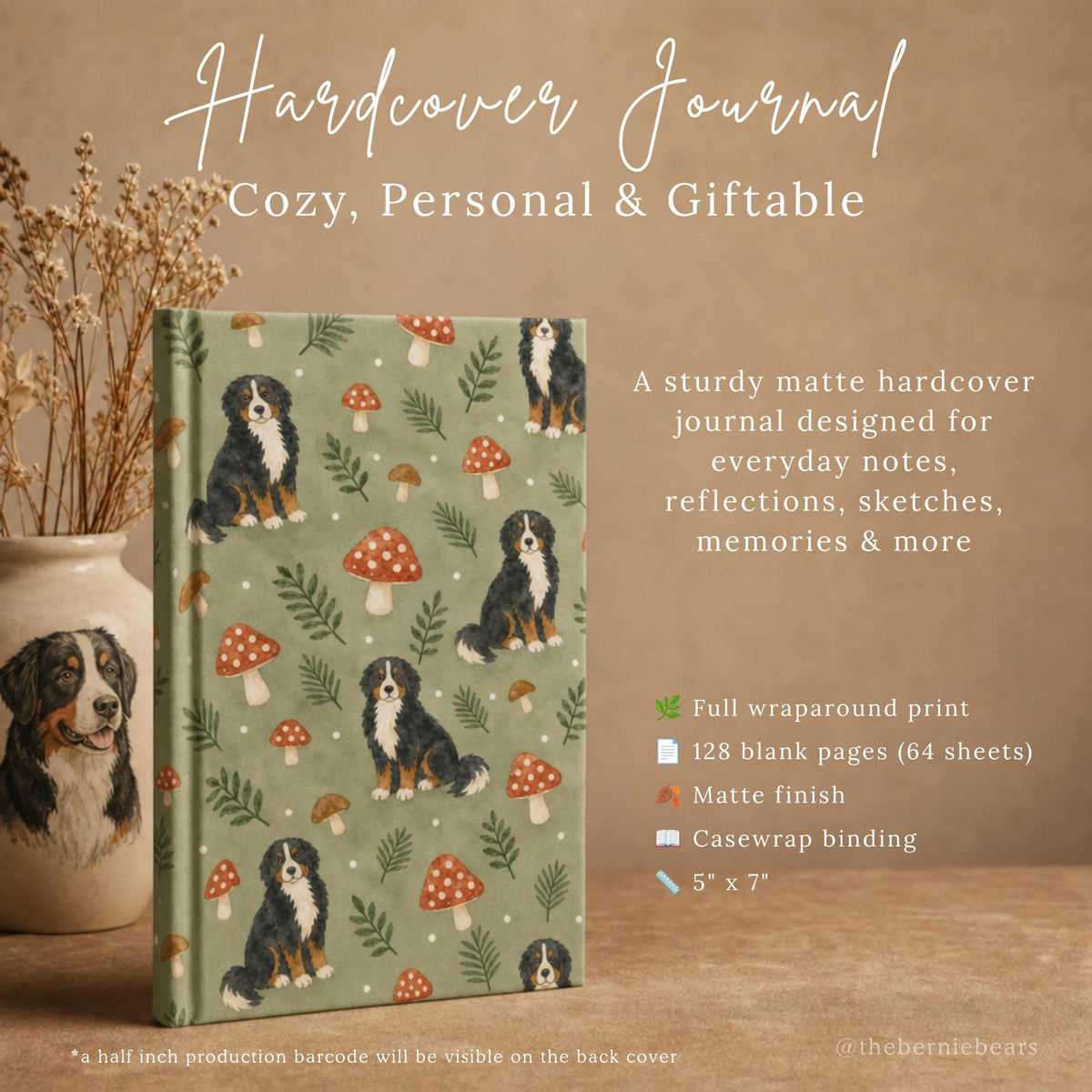  A hardcover journal featuring Bernese Mountain Dog puppies among toadstools and ferns on sage green, standing upright beside a ceramic vase painted with a Bernese Mountain Dog and dried florals, on a warm tan surface. Text reads "Hardcover Journal, Cozy, Personal & Giftable," with an icon list of full wraparound print, 128 blank pages, matte finish, casewrap binding, and 5 inches by 7 inches.